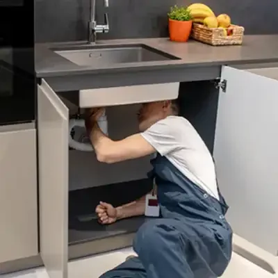 Bombeiro hidráulico realizando manutenção sob uma pia